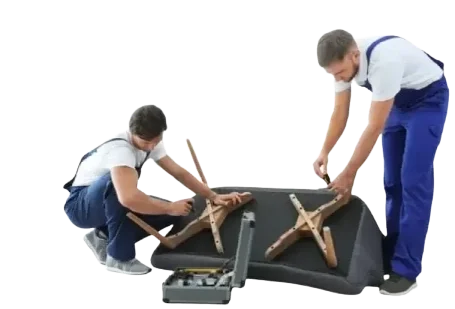 Two members of the Master Movers furniture assembly team are assembling an IKEA LANDSKRONA sofa, working together to attach the wooden legs. This image is from a flatpack assembly job in Greenford UB6.