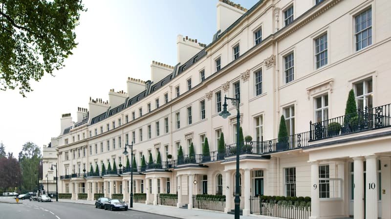 Elegant white stucco townhouses in Belgravia London along a quiet residential street, featuring classic Georgian architecture and private garden square surroundings