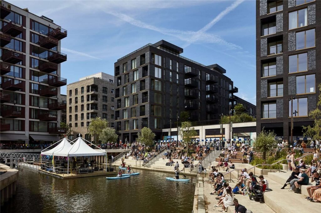 Brentford riverside development with modern apartment buildings, people relaxing by the canal and outdoor seating near Brentford Lock in West London